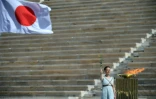 La flamme olympique devant le drapeau du Japon, pendant la cérémon ie de passation de la flamme entre la Grèce et le Japon dans un stade panathénaïque vide, le 19 mars 2020 à Athènes
