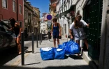 Carmo Pires (g) et ses deux filles portent des sacs de linge pour préparer des appartements pour les touristes à Alfama, quartier de Lisbonne, le 29 juin 2016