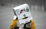 A boy wears a cardboard box on his head at a railway station in Shanghai 