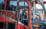 Un policier hongrois inspecte la carcasse du car immatriculé en Pologne qui a quitté la chaussée sur une autoroute hongroise faisant 12 morts et au moins 10 blessés graves, le 16 août 2026 près de Miskolc, dans le nord-est du pays 