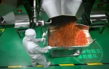 Un employé prépare des lamelles épicées pour leur conditionnement à l'usine Mala Wangzi du comté de Pingjiang, dans la province du Hunan, le 17 juin 2026 dans le centre de la Chine