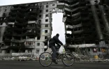 Un cycliste passe devant un bâtiment endommagé à Borodianka, au nord de Kiev, le 6 avril 2022