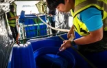 Des employés du service royal thaïlandais des précipitation ajoutent de l'eau et de la glace dans un conteneur pour les pulvériser dans l'air lors d'une mission de modification atmosphérique visant à déplacer la pollution, le 15 janvier 2025 à l'aéroport de Hua Hin, dans la province de Prachuap Khiri Khan