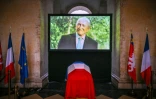 Le portrait de Gerard Collomb est diffusé sur un écran derrière le cercueil drapé du drapeau français de l'ex-maire de Lyon et ancien ministre de l'Intérieur, à l'hôtel de ville de Lyon, le 27 novembre 2023