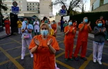 Des personnels soignants, salués par des habitants, applaudissent en retour, devant un hôpital de Madrid, le 12 avril 2020