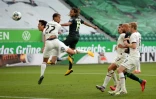 Le Suisse Kevin Mbabu (C) marque de la tête pour Wolfsbourg devant des tribunes vides recouvertes de bâches contre l'Eintracht Francfort le 30 mai 2020 à Wolfsbourg