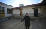 Une habitante de Jishinshan, dans la province chinoise de Gansu, devant une maison endommagée par le séisme, le 20 décembre 2023
