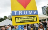 Une femme vêtue aux couleurs du drapeau américain brandit une pancarte disant "we love Trump" le 9 octobre sur la place des otages à Tel-Aviv, où des milliers de personnes se sont rassemblées pour fêter l'accord conclu entre Israël et le Hamas