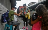 La Cubaine Diana Guzman, accompagnée de sa petite-fille Brianna, vend des bonbons dans une rue de Comayaguela, le 15 juin 2022 au Honduras