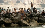 Des migrants sont assis sur des rochers après avoir traversé à la nage les eaux proches de la frontière avec le Maroc pour entrer dans l’enclave espagnole de Ceuta, en Afrique du Nord, le 31 juillet 2026