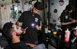 Un coiffeur utilise la lumière de son téléphone portable pour s'éclairer dans son salon, le 20 août 2021 à Beyrouth, au Liban