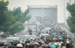 Des automobilistes et motocyclistes traversent une épaisse brume causée par des incendies de forêt et de terres sur le pont Duplikasi Jembatan Kapuas 1 à Pontianak, dans le Kalimantan occidental, le 7 octobre 2026 en Indonésie