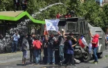 Des manifestants se tiennent devant un canon à eau de la police, à Santiago le 23 octobre 2019