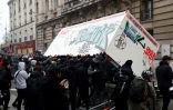 Des manifestants habillés tout en noir parviennent à renverser une remorque de chantier qui sera incendiée, à Paris le 5 décembre 2019