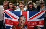 Des sympathisants de la famille royale tiennent un drapeau britannique décoré du portait du roi Charles III, à la veille de son couronnement, le 5 mai 2023 à Londres