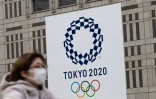 Une passante portant un masque, devant le logo des Jeux olympiques 2020, à Tokyo le 23 avril 2020