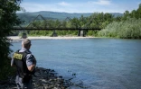 Un agent de la police des frontières roumaine inspecte la rive de la rivière Tisa avec en arrière plan le pont en bois reliant la Roumanie et l’Ukraine près du poste frontière de Sighetu Marmatiei, le 17 mai 2024