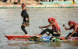 Rayyan Arkan Dikha danse à l'avant d'un bateau lors d'une course nautique traditionnelle, le 21 août 2025 sur la rivière Kuantan, dans la province indonésienne de Riau, sur l'île de Sumatra 