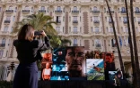 Une femme prend une photo d'un écran géant faisant la promotion du film "Mission : Impossible - The Final Reckoning" avec l'acteur américain Tom Cruise devant l'hôtel Carlton, à Cannes, dans le sud de la France, le 13 mai 2025