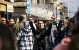 Une femme tient une pancarte "Les Alaouites sont nos frères et notre famille" lors d'une manifestation de masse dans la ville de Qamishli, au nord-est de la Syrie, le 11 mars 2025, pour protester contre une récente vague de violence visant la minorité alaouite de Syrie dans l'ouest du pays