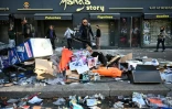 Un commerçant déblaie les débris devant sa boutique vandalisée au lendemain d'une manifestation contre la vie chère, le 18 octobre 2026 à Paris