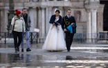 Un couple tout juste marié traverse une place inondée, à Venise le 14 novembre 2019