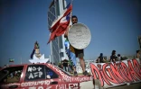 Un homme brandit un drapeau chilien et un bouclier de fortune lors d'une manifestation anti-gouvernementale commémorant également la mort un an auparavant d'un Mapuche tué par la police, à Santiago le 14 novembre 2019