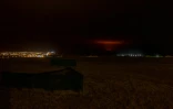 Un nuage rouge du magma lâché par le volcan Fagradalsfjall s'élève derrière la ville de Keflavik et l'aéroport international, à environ 50 km à l'ouest de la capitale de l'Islande, Reykjavik, le 19 mars 2021