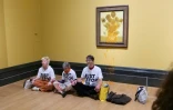 Photo fournie par l'organisation écologiste Just Stop Oil montrant trois militants devant un tableau des "Tournesols" de Vincent van Gogh aspergé de soupe, à la National Gallery à Londres, en septembre 2024