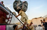 Des réfugiés afghans, expulsés du Pakistan, chargent leurs affaires dans un bus à Karachi, le 8 avril 2025, avant leur départ pour l'Afghanistan