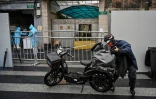 Un livreur en scooter apporte une commande à l'entrée d'un quartier confiné de Shanghai après l'apparition de nouveaux cas de Covid-19, le 17 mars 2022 en Chine