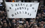 La foule brandit une pancarte "Merci Johnny Hallyday", le 9 décembre 2017 devant l'Eglise de la Madeleine à Paris