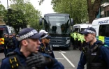 Des policiers escortent, lors d'une manifestation, un bus qui conduirait des migrants et des demandeurs d'asile d'un hĂ´tel de Peckham, au sud de Londres, vers la barge Bibby Stockholm Ă Portland, dans le Dorset, au sud-ouest de l'Angleterre, le 2 mai 2024