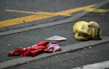 Une peluche et un drapeau de Liverpool gisent sur la chaussée, derrière un cordon de police, sur Water Street à Liverpool, dans le nord-ouest de l'Angleterre, le 27 mai 2025, après qu'une voiture a foncé sur la foule la veille
