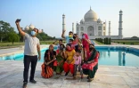 Un groupe de touristes prend des photos devant le Taj Mahal au premier jour de sa réouverture à Agra en Inde le 16 juin 2021