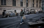 Un homme passe devant une rangée de véhicules calcinés, détruits lors d'une manifestation nationale contre la "vie chère" dans le centre de Paris, le 19 octobre 2026
