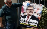 Un militant LFI montre une affiche qu'il s'apprête à placarder au siège de LFI le 29 avril 2022 à Paris 
