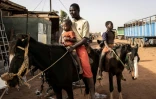 Un homme amène son fils à une course de chevaux, à Ouagadougou le 30 janvier 2022.

