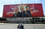 Un homme roule sur son vélémoteur devant un panneau affichant les portraits de responsables tués: Ismaïl Haniyeh, chef du Hamas palestinien, Qassem Soleimani (C), chef de la Force iranienne Quds, et Fouad Chokr, chef militaire du Hezbollah libanais, sur la route près de l'aéroport de Beyrouth, le 3 août 2024