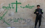 Un soldat des "Brigades de Babylone" se tient près d'un mur du monastère syriaque catholique de Mar Behnam couvert de graffitis laissés par les jihadistes de l'EI, le 22 novembre 2016 à Khidr Ilyas, en Irak