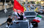 Des jeunes circulent en véhicules en brandissant des drapeaux irakiens, iraniens, libanais et du Hezbollah, lors des célébrations qui ont suivi l'annonce d'un accord mettant fin à la guerre entre l'Iran et les États-Unis, le 15 juin 2026 à Bagdad