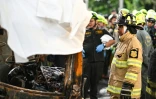 Des pompiers autour de la carcasse d'un bus détruit par un incendie, qui a fait plusieurs morts parmi des écoliers en voyage scolaire, dans la banlieue de Bangkok, en Thaïlande, le 1er octobre 2024