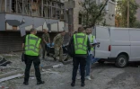 Le corps d'une victime est transporté dans un van à côté d'un immeuble résidentiel endommagé à la suite d'une frappe russe à Kiev, le 20 août 2026