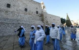 Des religieuses et moines chrétiens passent devant l'église de la Nativité à Bethléem, en Cisjordanie occupée, avant les célébrations de Noël, le 24 décembre 2025
