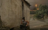 Une femme porte un seau d'eau alors qu'un incendie fait rage à Busturenga, dans la région d'Aveiro, dans le nord du Portugal, le 16 septembre 2024