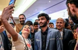 Un fan prend un selfie avec le grand maître indien Gukesh Dommaraju (c.) après sa victoire contre le grand maître chinois Ding Liren dans la 14e partie du Championnat du monde d'échecs, à Singapour, le 12 décembre 2024