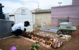 Un homme dispose des coquillages sur une tombe dans le cimetière de Sainte-Rose-de-Lima, à Sainte-Rose en Guadeloupe, le 31 octobre 2025