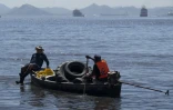Des pêcheurs transportent en bateau des pneus ramassés sur les plages de l'île de Pombeba, dans la baie de Guanabara, le 17 février 2025 à Rio de Janeiro, au Brésil