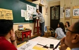 Le calligraphe Nguyen Thanh Tung (c) enseigne la calligraphie à des étudiants, chez lui à Hanoï, le 15 mai 2025 au Vietnam
