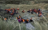 Des migrants, cachés dans les dunes, attendent le bateau d'un passeur et tenter de traverser la Manche au large de la plage de Gravelines, le 16 juin 2025 dans le Nord
